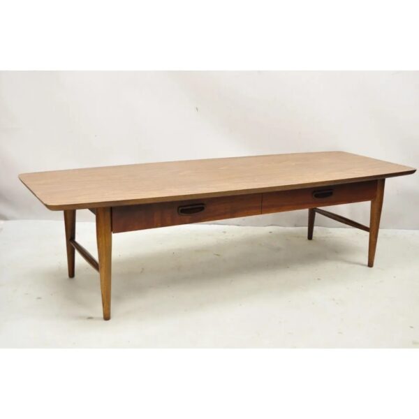 A rectangular wooden coffee table with tapered legs and two drawers featuring black oval handles, set against a plain white background.