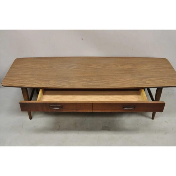 A rectangular wooden coffee table with tapered legs and an open drawer featuring two handles, revealing storage space inside.