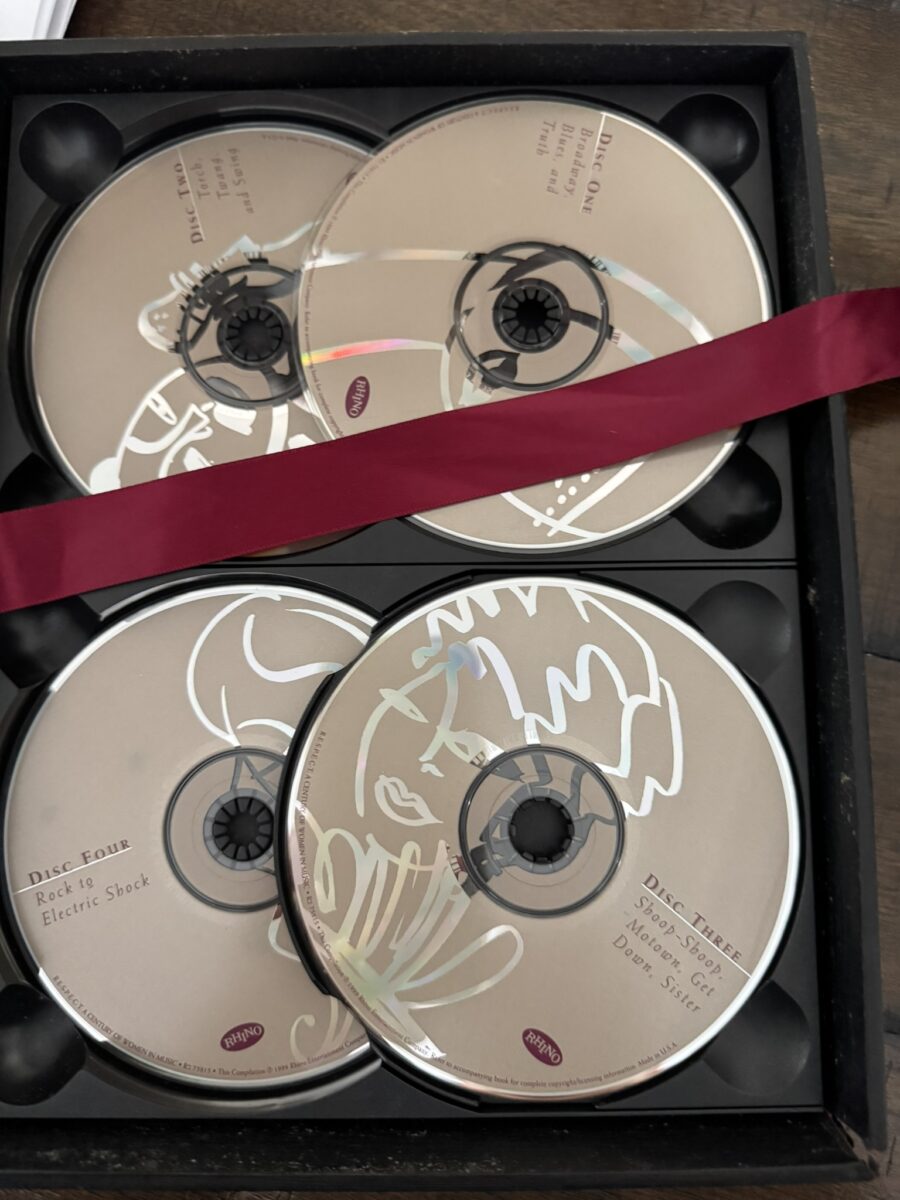 The RESPECT Women in Music Box Set features four CDs with minimalist line art and text, arranged in a black case. Each disc celebrates Women in Music, and a dark red ribbon crosses the box above the bottom two CDs.