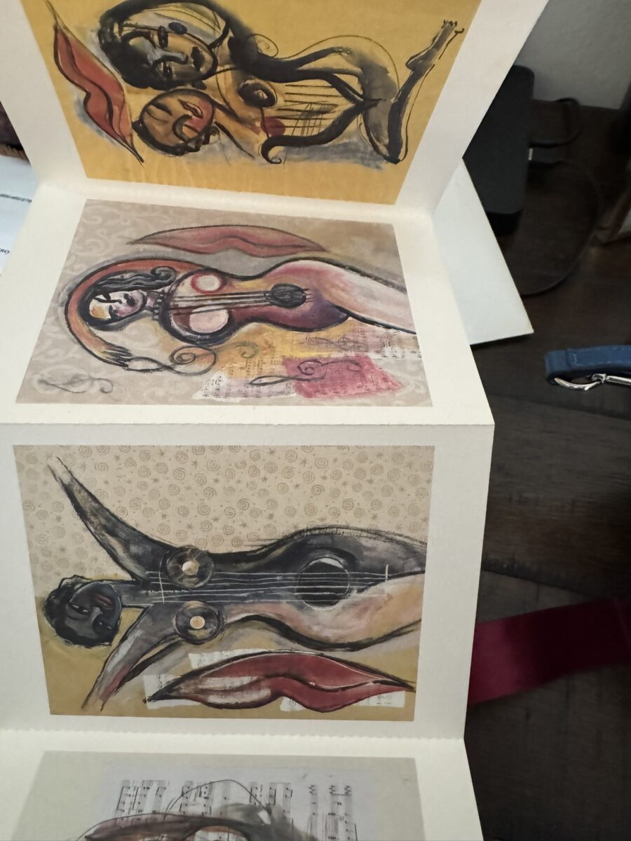 The RESPECT Women in Music Box Set features a vertical fold-out card displaying three abstract paintings of women with musical notes and red lips on warm backgrounds, celebrating Women in Music with a desk shown behind the card.