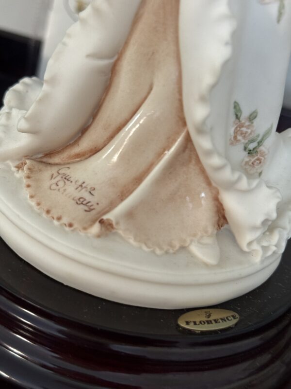 Close-up of the Armani Flower Dress Figurine in a flowing floral dress. The base shows Giuseppe Armani’s engraved signature, a gold 