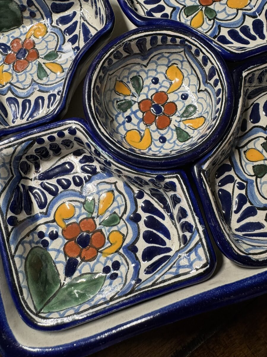 Colorful hand-painted ceramic dishes with floral patterns in blue, yellow, green, and red. The set includes square and round compartments bordered in dark blue, fitting together on a tray. The intricate designs feature leaves and stylized flower motifs.
