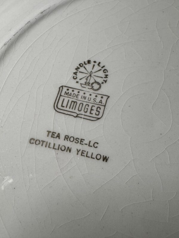 Close-up of the makers mark on a piece of white ceramic with visible crackle texture. The stamp reads “CANDLELIGHT MADE IN U.S.A. LIMOGES,” and below that, “TEA ROSE–LC COTILLION YELLOW” in capital letters.