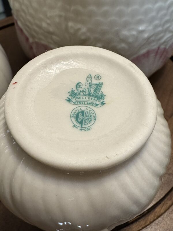 The bottom of a white ceramic dish is shown. It features a green printed Belleek Ireland trademark with a harp, shamrocks, and a tower. The text reads BELLEEK, IRELAND, REG. No 0857 and is surrounded by intricate design details.