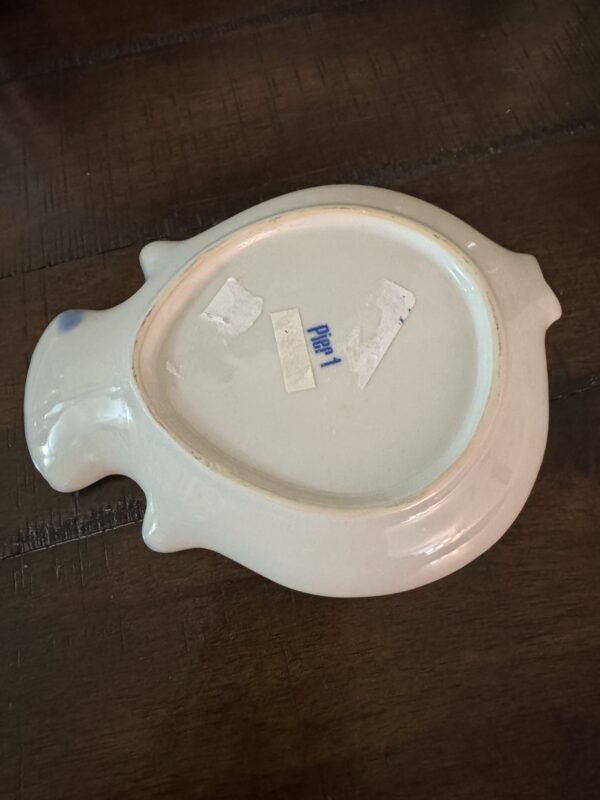 A Woulind Chile Serving Dish shaped like a fish is shown upside down on wood. The pale cream dish features a faint blue spot on its tail, two partially removed stickers, and 