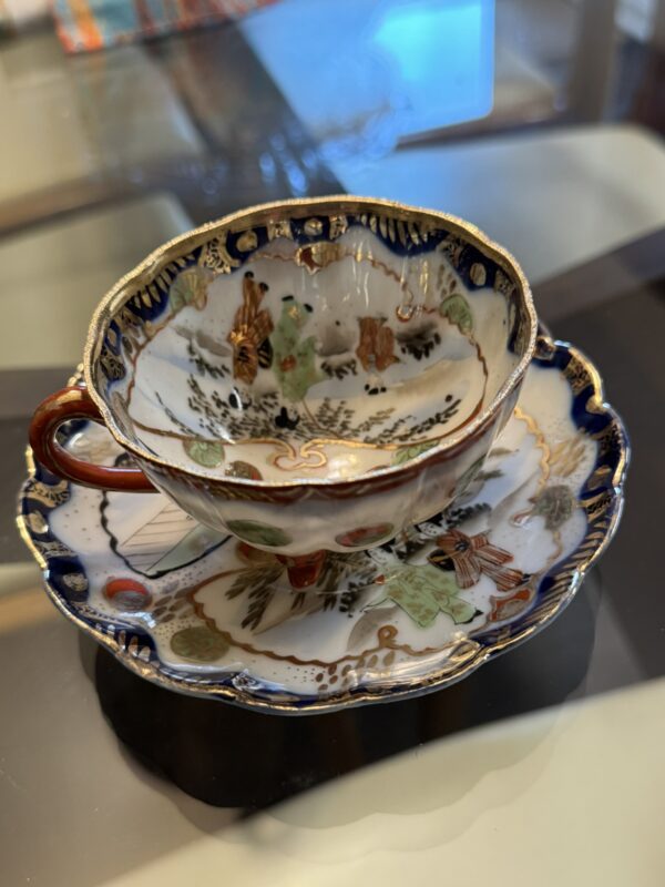 The Woulind Chile Serving Dish features scalloped edges and deep blue with gold detailing, inspired by classic designs. Its hand-painted floral and bird motifs in green, red, and gold add elegance to any table setting.