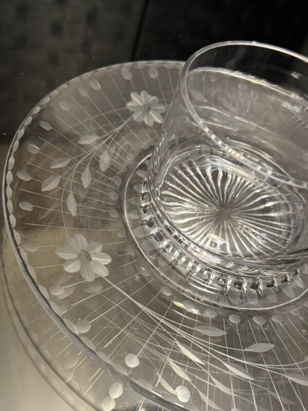 The Woulind Chile Serving Dish features a clear glass cup on a matching dish, both adorned with etched floral, leaf, and radiating line patterns that create a delicate effect as light reflects on the intricate glass details.
