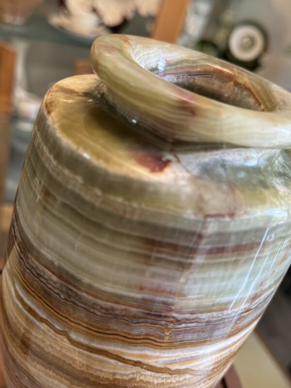 A close-up of the Woulind Chile Serving Dish shows its polished stone with layered bands of green, brown, cream, and rust. The rounded lip and glossy finish highlight natural striations against a softly blurred background.