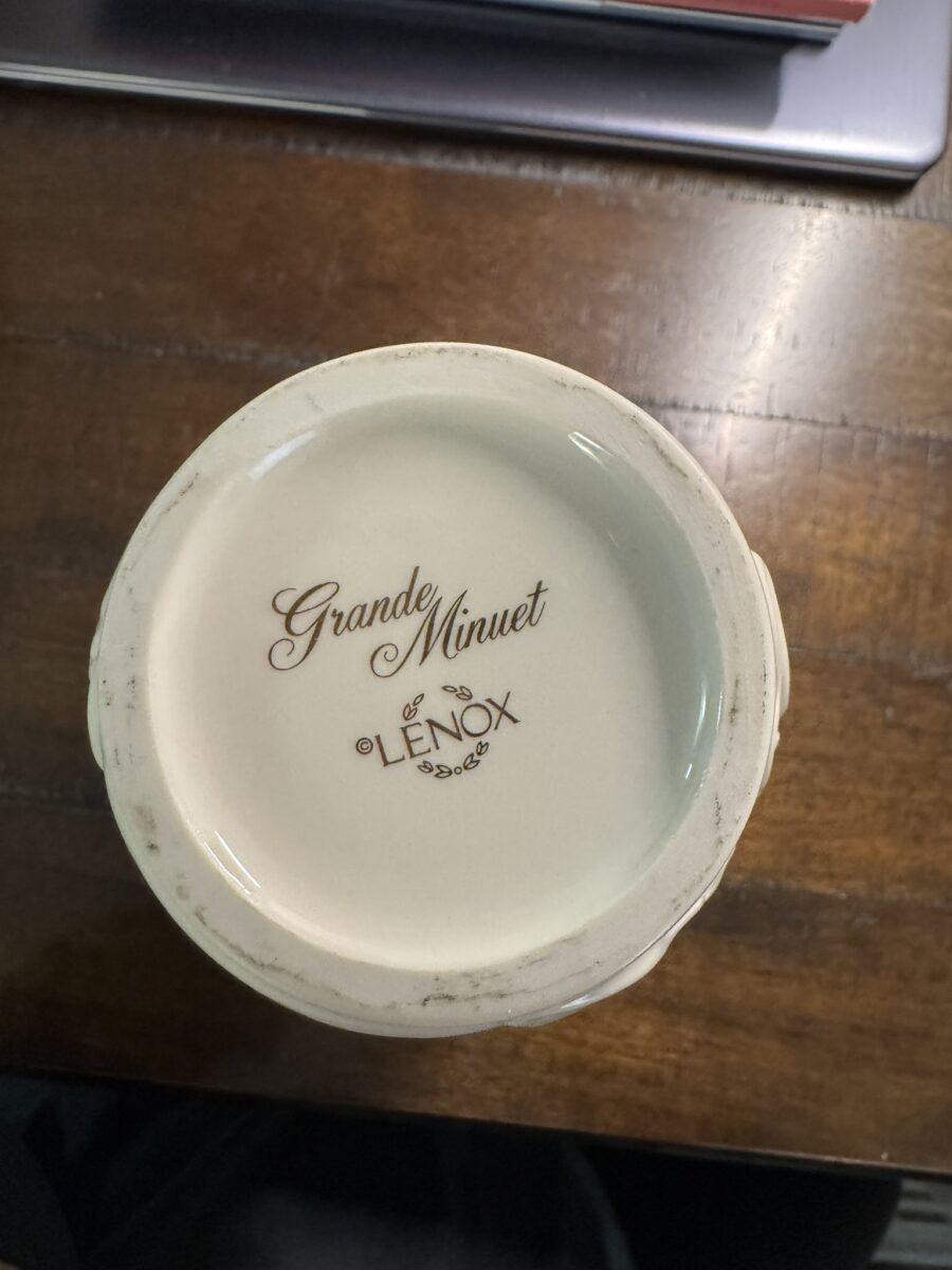 A cream-colored Woulind Chile Serving Dish made of porcelain is shown on a dark wooden surface. The base displays "Grande Minuet" and "Lenox" in script, with decorative flourishes. Edges have slight wear and discoloration.