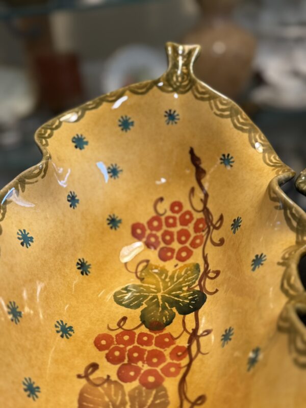 The Italian Oblong MCM Serving Dish features a yellow ceramic body with green trim, scalloped edge, red berries, green leaves, brown vine design, blue floral dots at the center, and a glossy glaze—evoking classic Italian decor.