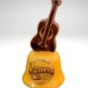 The Opryland Guitar Bell is a ceramic souvenir with a brown guitar handle and a yellow base labeled "Grand Ole Opryland USA, Home of American Music, Nashville, Tennessee," featuring musical notes in vintage style.