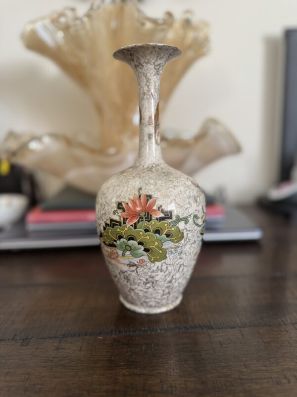 The Chinese Blue & White Miniature Vase sits on a dark wooden surface, featuring intricate blue floral patterns on its crackle-glazed background. Its elegant artistry adds a refined touch to any space.