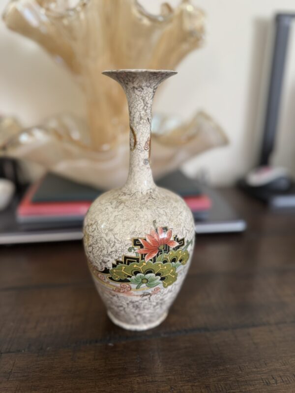 A petite Chinese Blue & White Miniature Vase with a slender neck and intricate blue floral patterns sits on a dark wooden table, with blurred books and a glass ornament visible in the background.