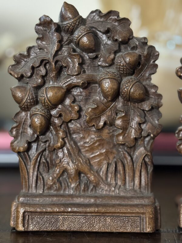 A decorative metal bookend showcases raised oak leaves and acorns, echoing motifs from the Chinese Blue & White Miniature Vase. A mottled bronze-brown finish adds vintage charm to its detailed, ridged rectangular base.