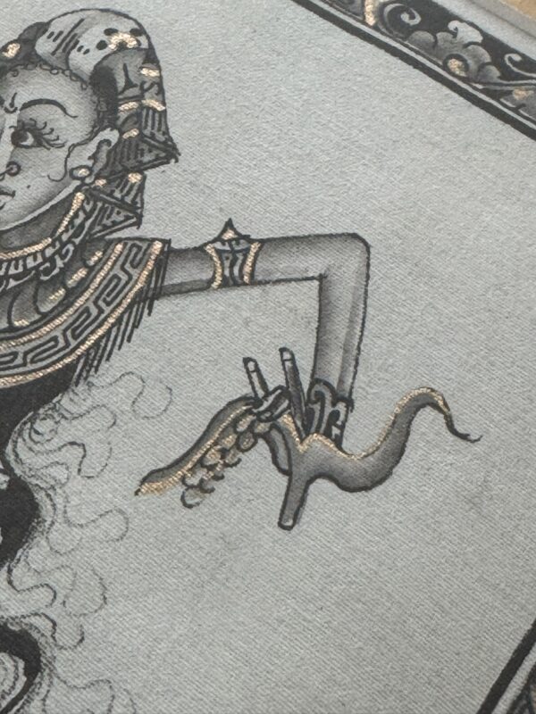 A grayscale illustration on textured fabric shows an ornate, stylized figure in profile wearing detailed jewelry. The figure’s slender arm is bent upward, with long fingers delicately holding a gold-outlined animal resembling a horse or deer.
