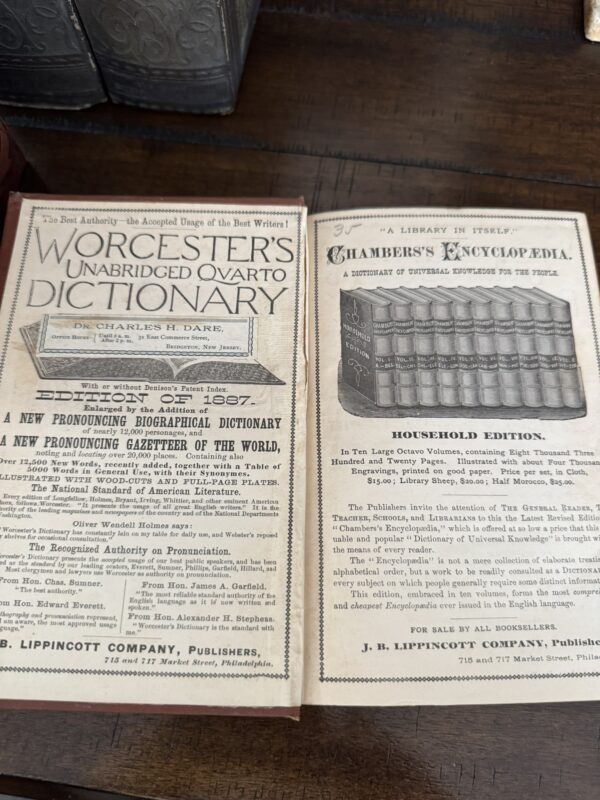 Two vintage book ads are shown. The left page advertises Worcester’s Unabridged Quarto Dictionary, with dense text and a decorative border. The right page advertises Chamber’s Encyclopaedia, featuring an illustration of books on a shelf above product details.