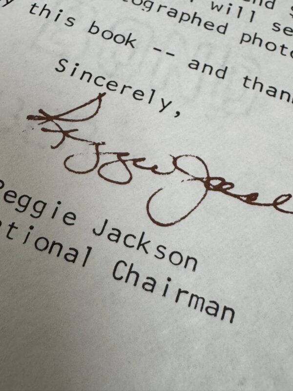 A close-up of a typed letter shows a handwritten signature in brown ink above the printed name Peggie Jackson and the title National Chairman. The word Sincerely, is visible above the signature. The paper shows some shadowing from lighting.