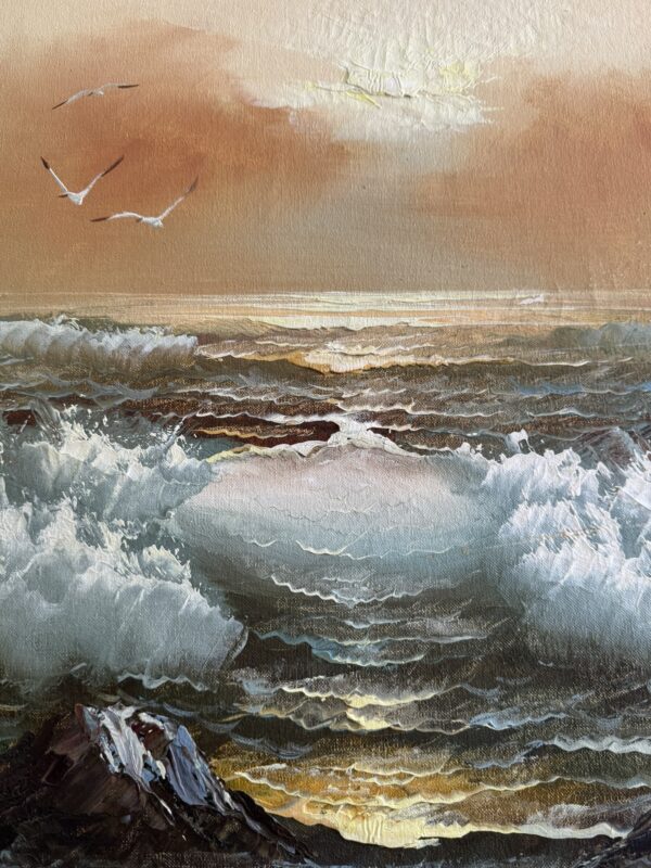 A painting of a seascape at sunset shows waves crashing, with sunlight reflecting on the water. Three seagulls fly in the sky, and warm orange and yellow tones fill the sky above the ocean. Rocks appear in the lower-left foreground.