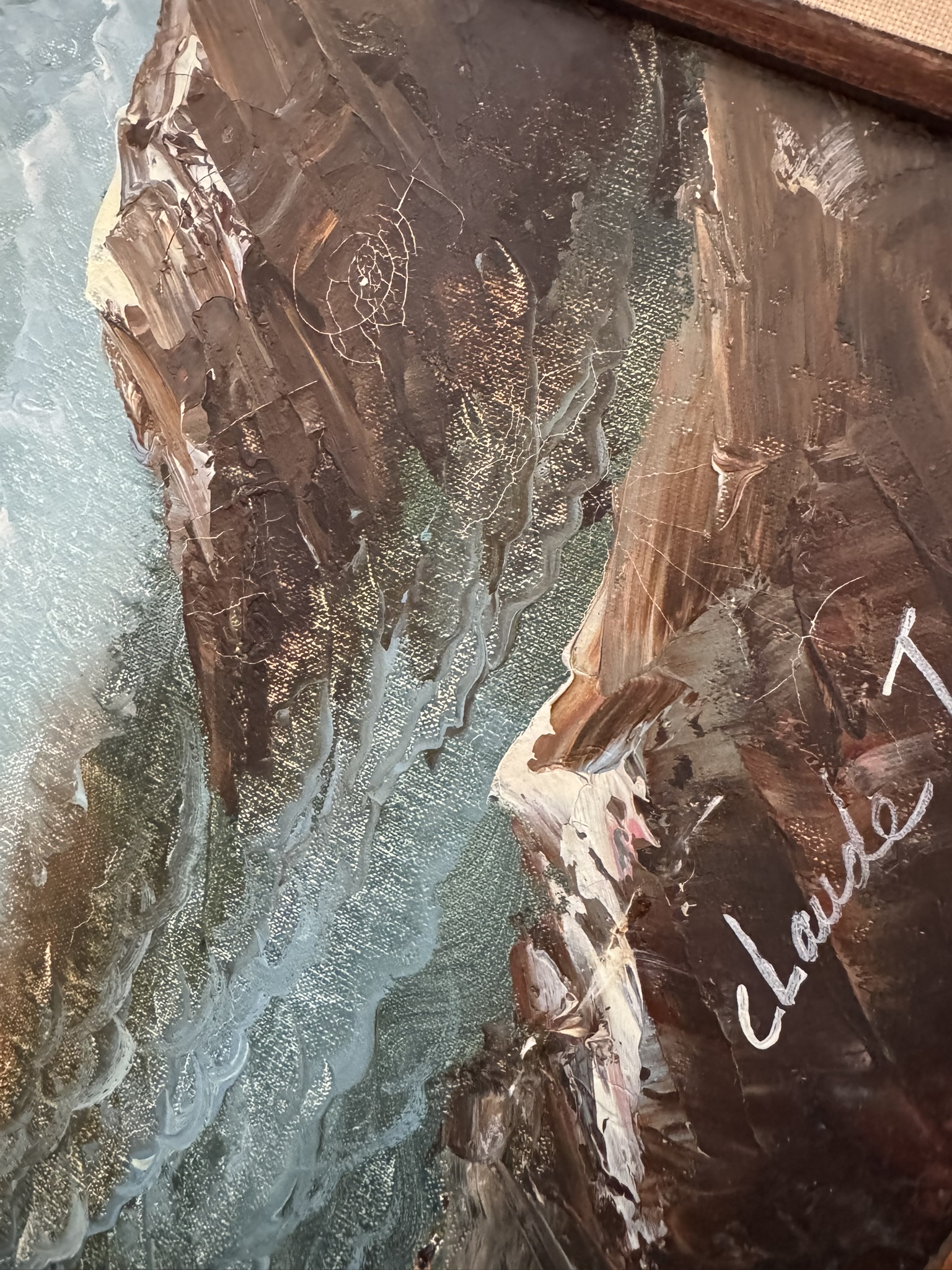A close-up of a textured painting shows a blue river running between rocky, brown cliffs. Visible brushstrokes and paint textures create depth. The artist’s signature, claude T, is written in white in the lower right corner, partially on the cliff.