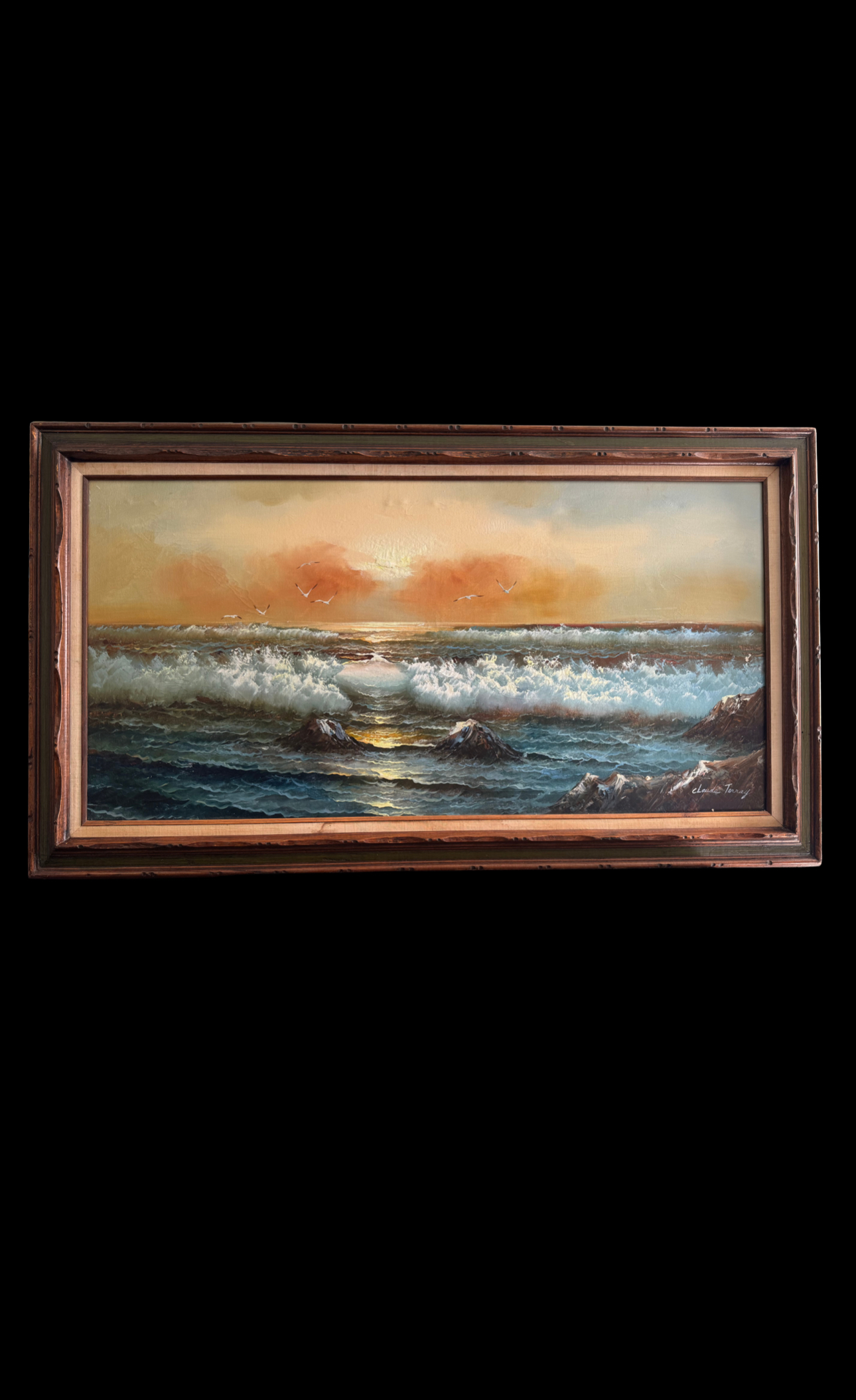 A framed painting of an ocean scene at sunset. Waves crash onto rocks in the foreground, with white foam visible. The sun is low on the horizon, casting golden light on the water. The sky is orange and yellow with scattered clouds and birds flying above the sea.